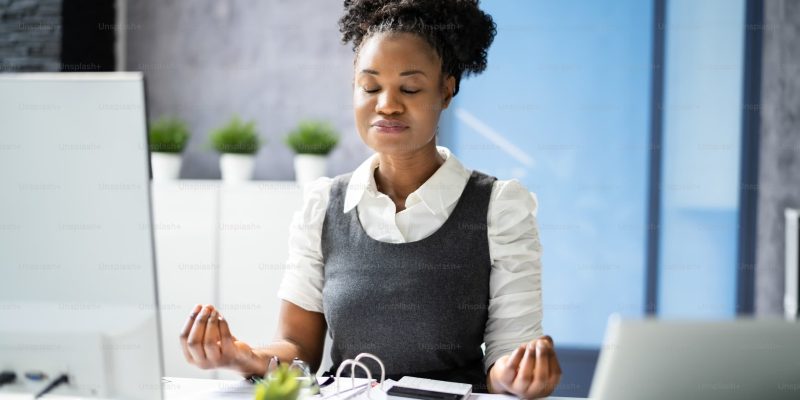 Suistanable performance - Businesswoman practicing mindfulness at her desk to balance performance and wellbeing.